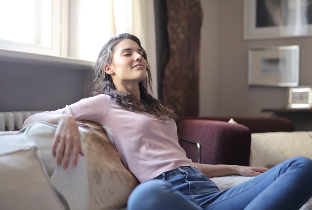 Woman relaxing on a couch in a cozy living room, embodying tranquility and comfort.